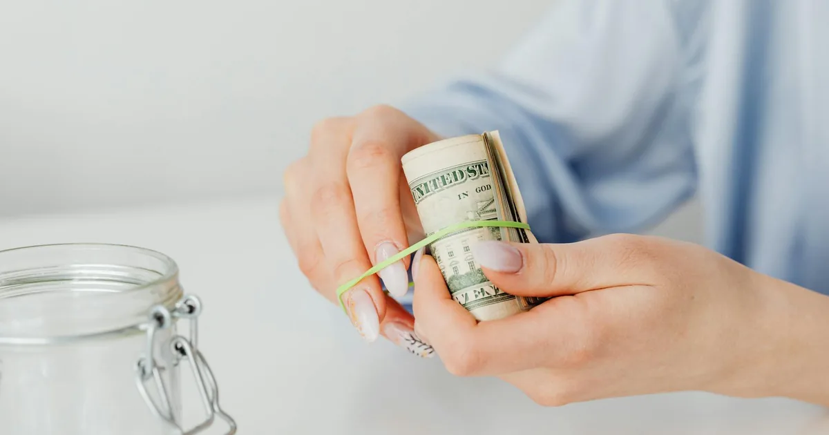 A person setting aside cash in a savings jar